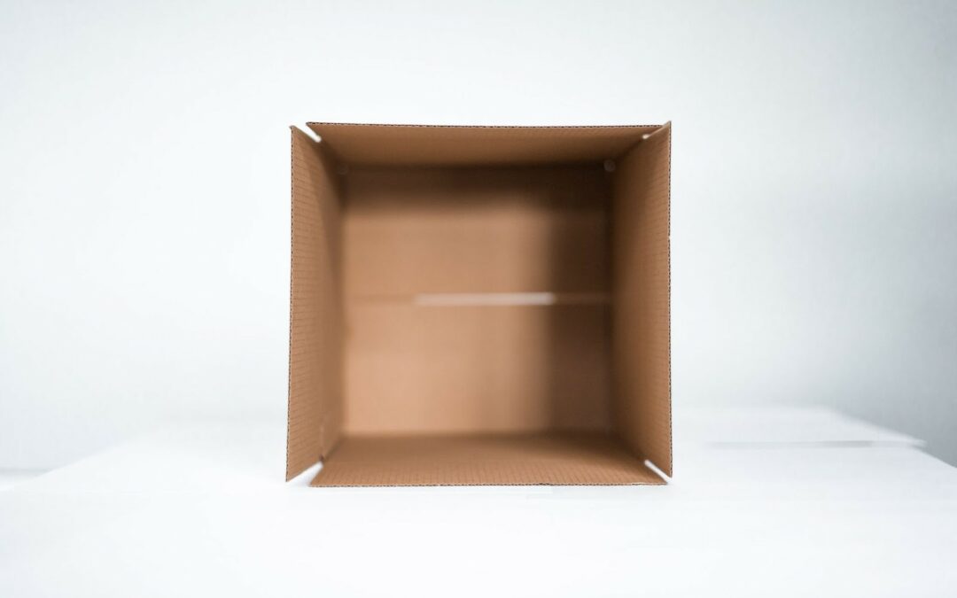 An empty, opened box, lying on its side on a white surface.